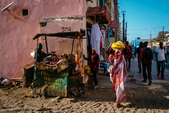Woman buying meat at a butcher shop while people are walking