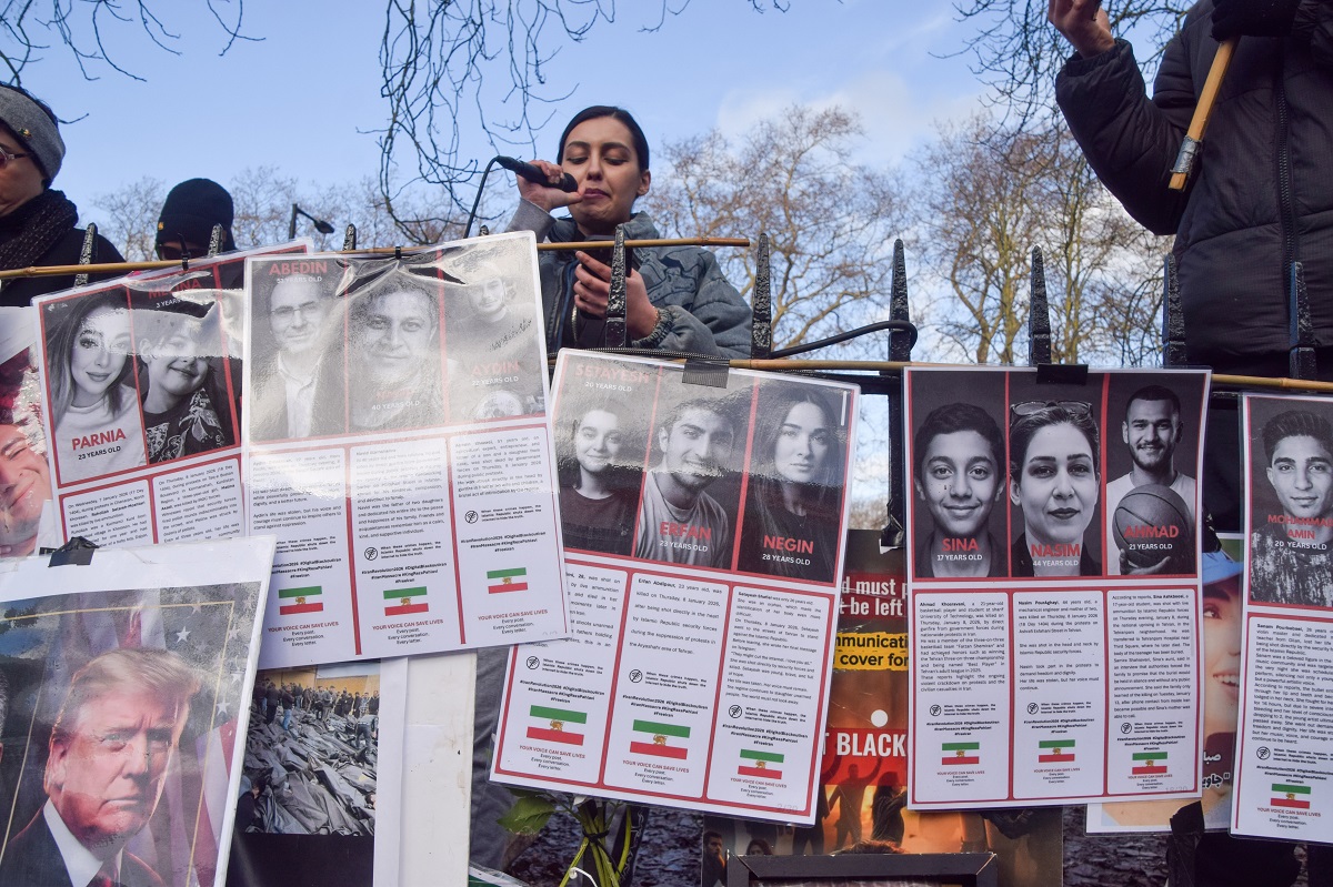 A protester gives a speech next to pictures of the victims