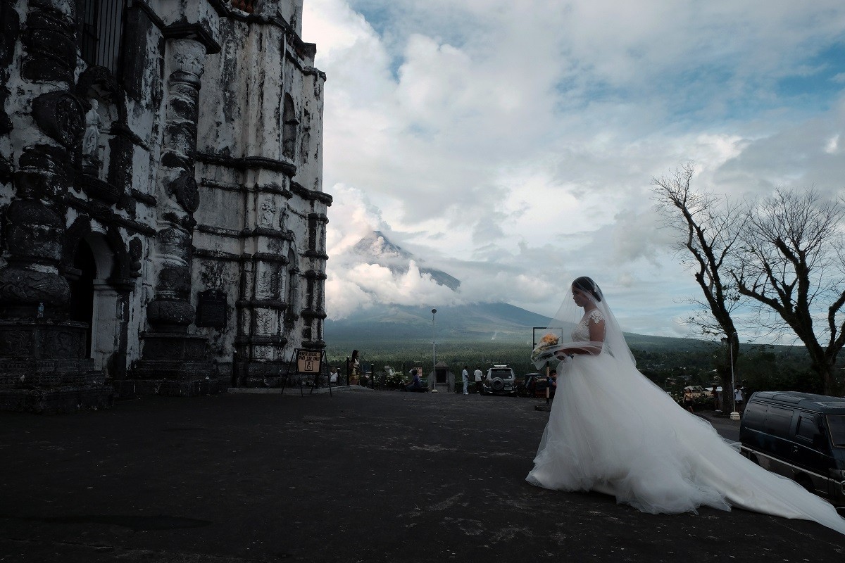 A bride seen having her wedding photos done before the Mayon